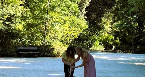 Girl learning ancient balance game with facilitator in Athens.