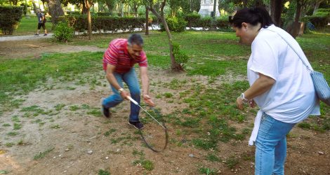 Parents balancing a wheel with a stick in Athens’ National Garden.