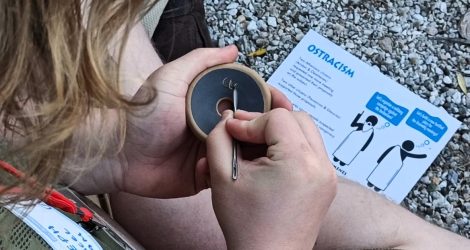 Participant engraves ostracon during ostracism activity on Pnyx Hill.