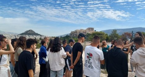 High school students tour on Pnyx Hill with Acropolis view.